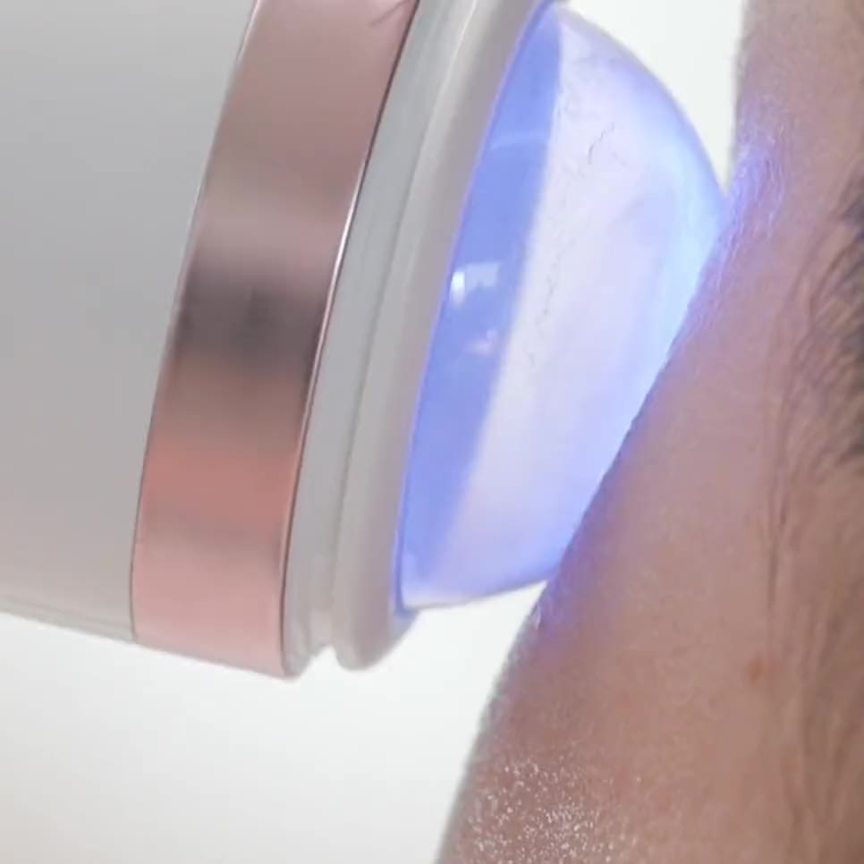 The plasma head, lit blue, held against the skin