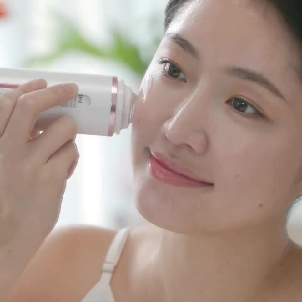 A woman holds the rolling applicator against her cheek